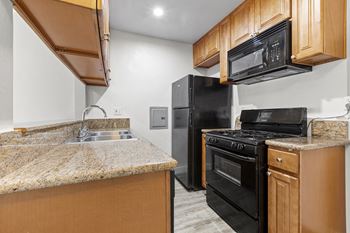 A kitchen with black appliances and granite counter tops